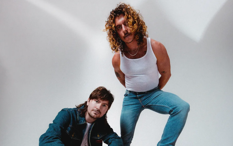 Australian electronic music duo Peking Duk members Adam Hyde and Reuben Styles posing against a plain light backdrop for a promo photo shoot.